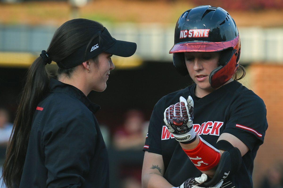 Senior infielder Kaylee Lambrecht (right) speaks with assistant coach Grayson Radcliffe (left) after making it to first base during the game against Elon at Dail Softball Stadium on Tuesday, April 2, 2024. Lambrecht had one at bat and two runs. NC state won the game 12-2.