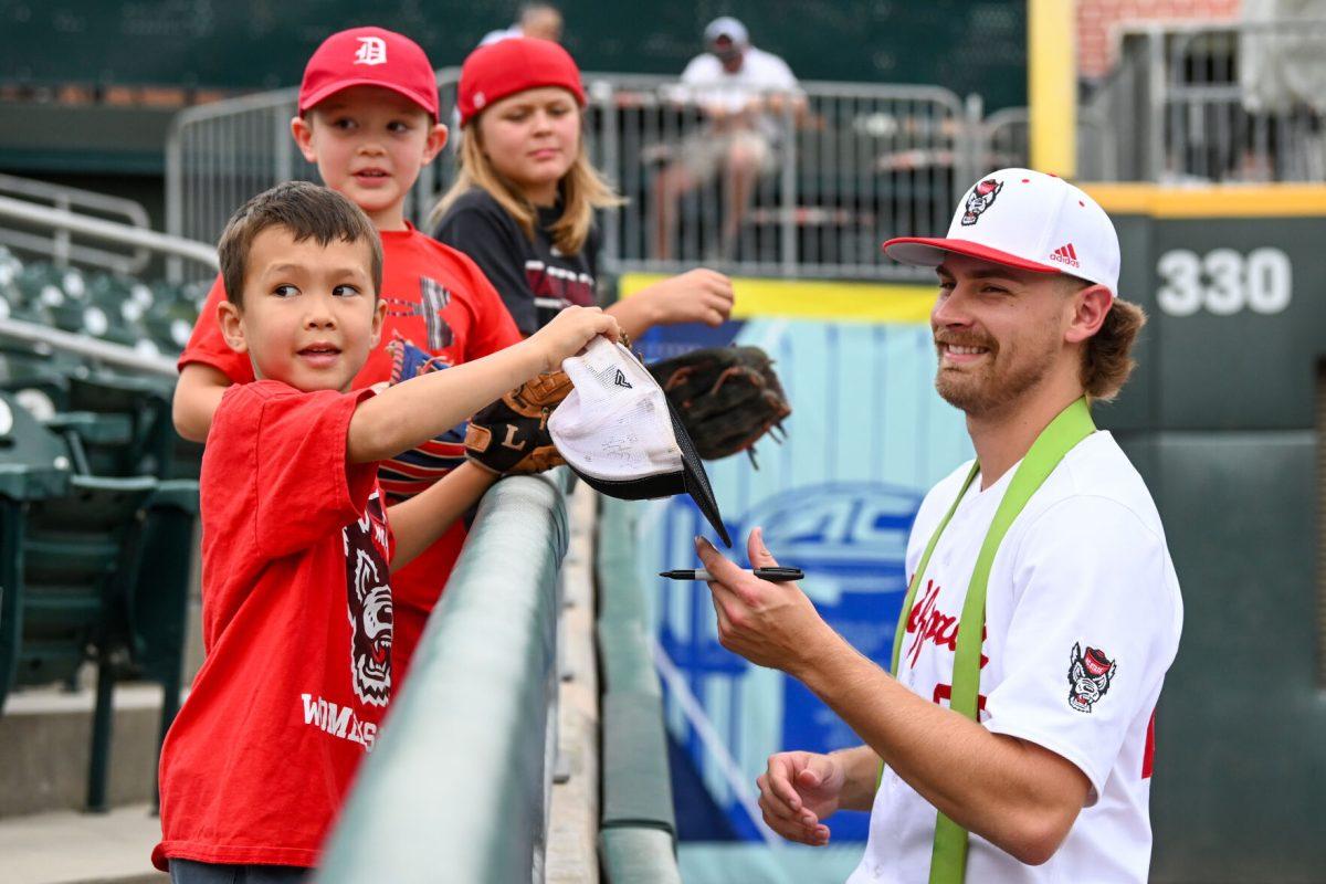 Redshirt senior pitcher Logan Whitaker signs hats and balls while warming up before the ACC Tournament game against Duke at Truist Field in Charlotte on Thursday, May 23, 2024. NC State lost to Duke 8-1.