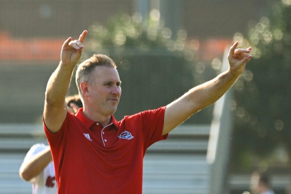 Head coach Marc Hubbard holds up "wolfies" after the match against Florida Gulf Coast University at Dail Soccer Field on Sunday, Aug. 25, 2024. NC State won 1-0.