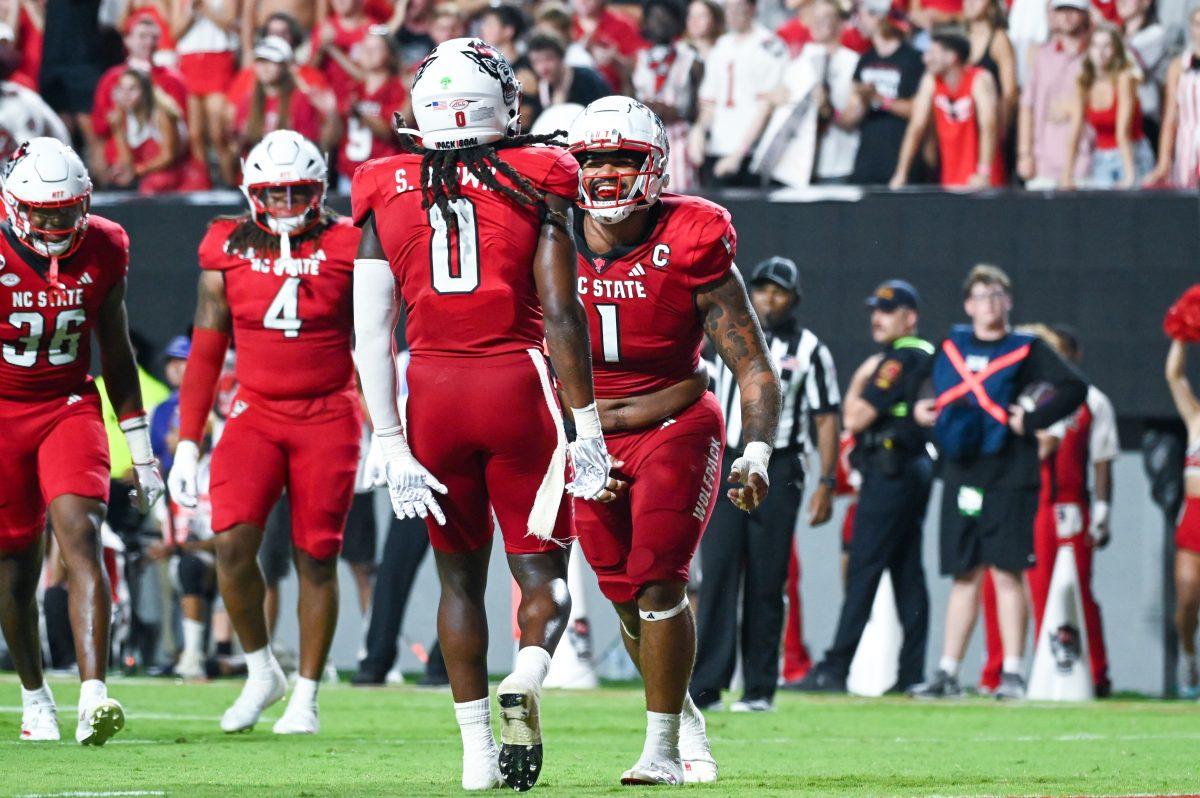 Graduate defensive end Davin Vann and redshirt junior linebacker Sean Brown celebrate a big stop during the game against Western Carolina at Carter-Finley Stadium on Thursday, Aug. 29, 2024. The Wolfpack defeated the Catamounts 38-21.