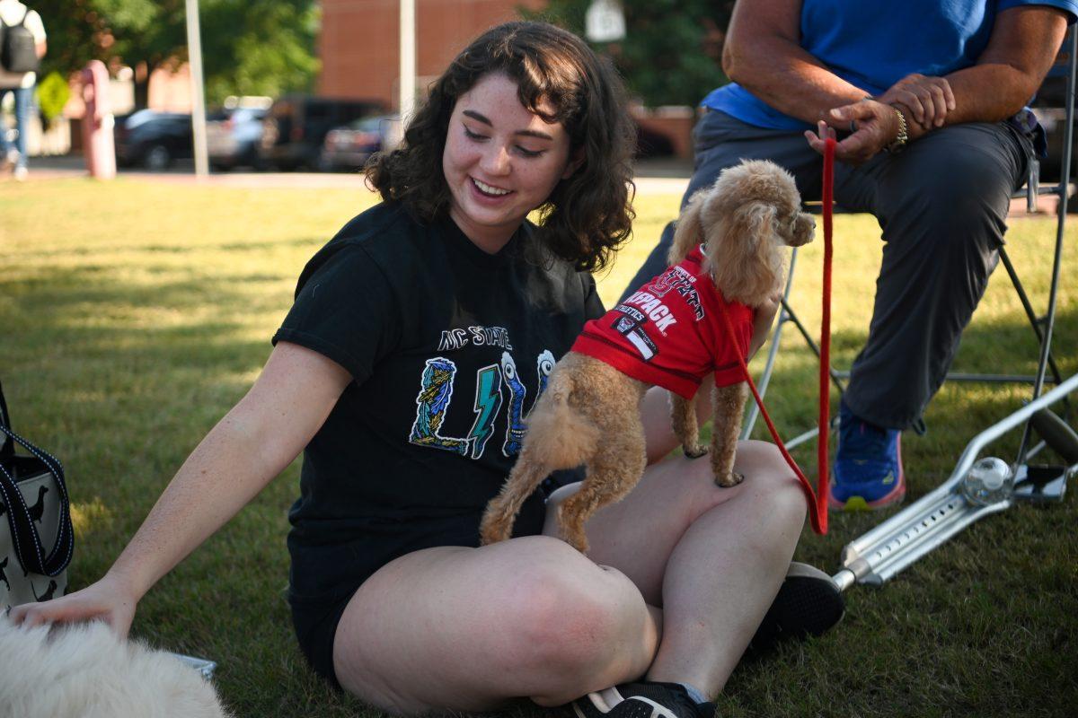 Katie Schwartz, a second-year studying international studies, pets dogs during the Puppies &amp; Politics event at Harris Field on Tuesday, Sept. 10, 2024. The event was hosted by BridgeNCSU, an organization focused on civil discourse.