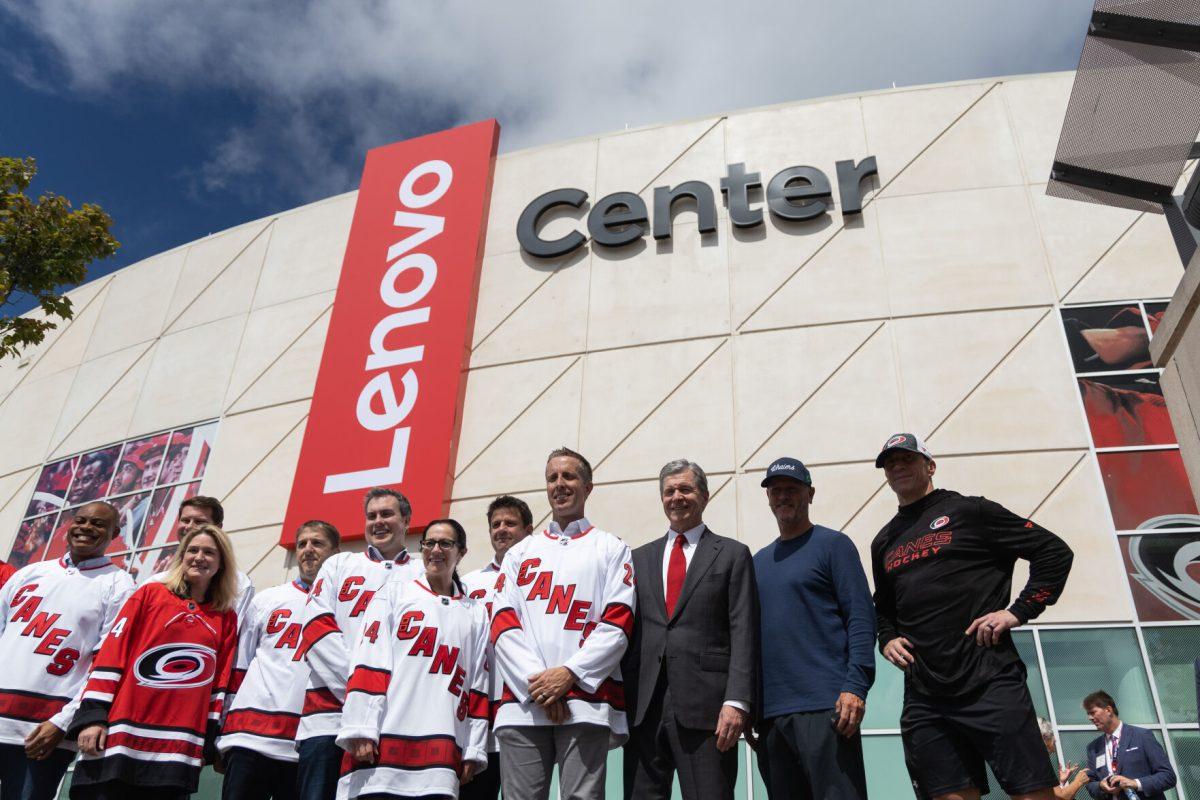 Lenovo executives, Governor Cooper and Carolina Hurricanes&#8217; Tom Dundon and head coach Rod Brind'Amour pose in front of the new sign at the Lenovo Center unveiling on Thursday, Sept. 19, 2024. The event hosted Lenovo employees and members of the NC Centennial Authority.