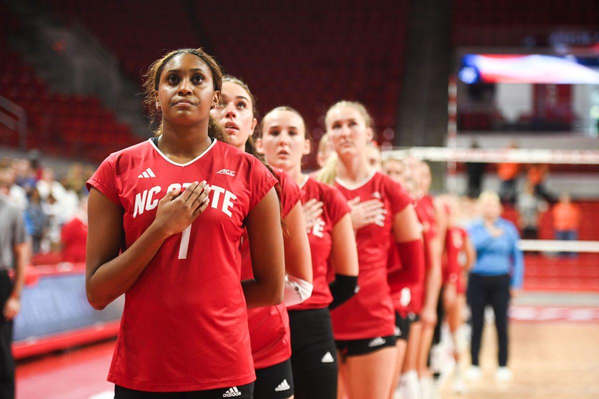 Redshirt senior opposite hitter Madison Williams stands with her teammates looking at the flag during the United States National Anthem before the NC State Wolfpack women's volleyball team's game against the Virginia Cavaliers at Reynolds Coliseum on Sunday, Sept. 29, 2024. The Wolfpack went on to defeat the Cavaliers 3-1.