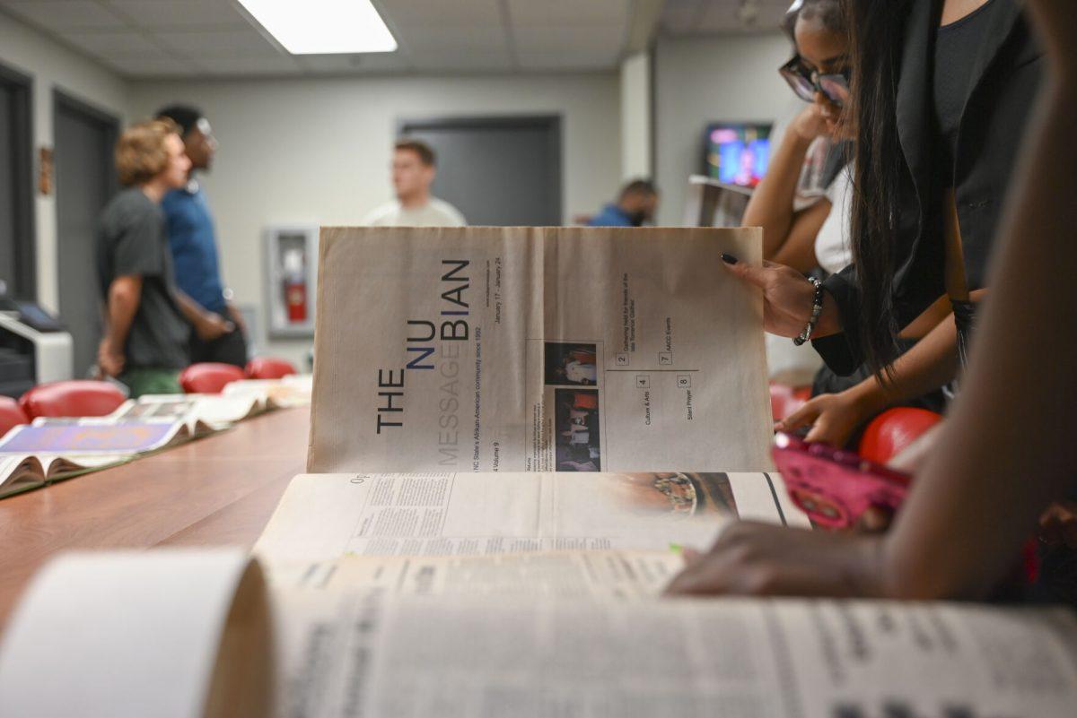 Students flip through past editions of the Nubian Message during the Nubian Message Launch Party in the African American Cultural Center on Thursday, Sept. 12, 2024. The Nubian Message celebrated the return of "The" to the organization's name and looked back at the organization's history and impact on campus.