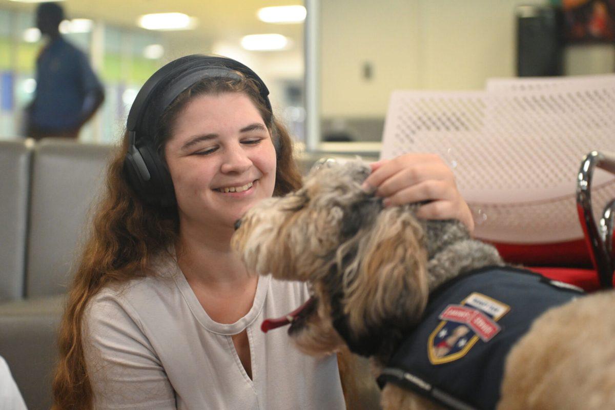 Alexandra Cohen, a third-year studying crop and soil science, smiles while petting Barkley at Pause for Paws at D.H. Hill Jr. Library on Tuesday, Sept. 17, 2024. Pause for Paws was an event organized by Prevention Services that allowed students to relax with therapy dogs.
