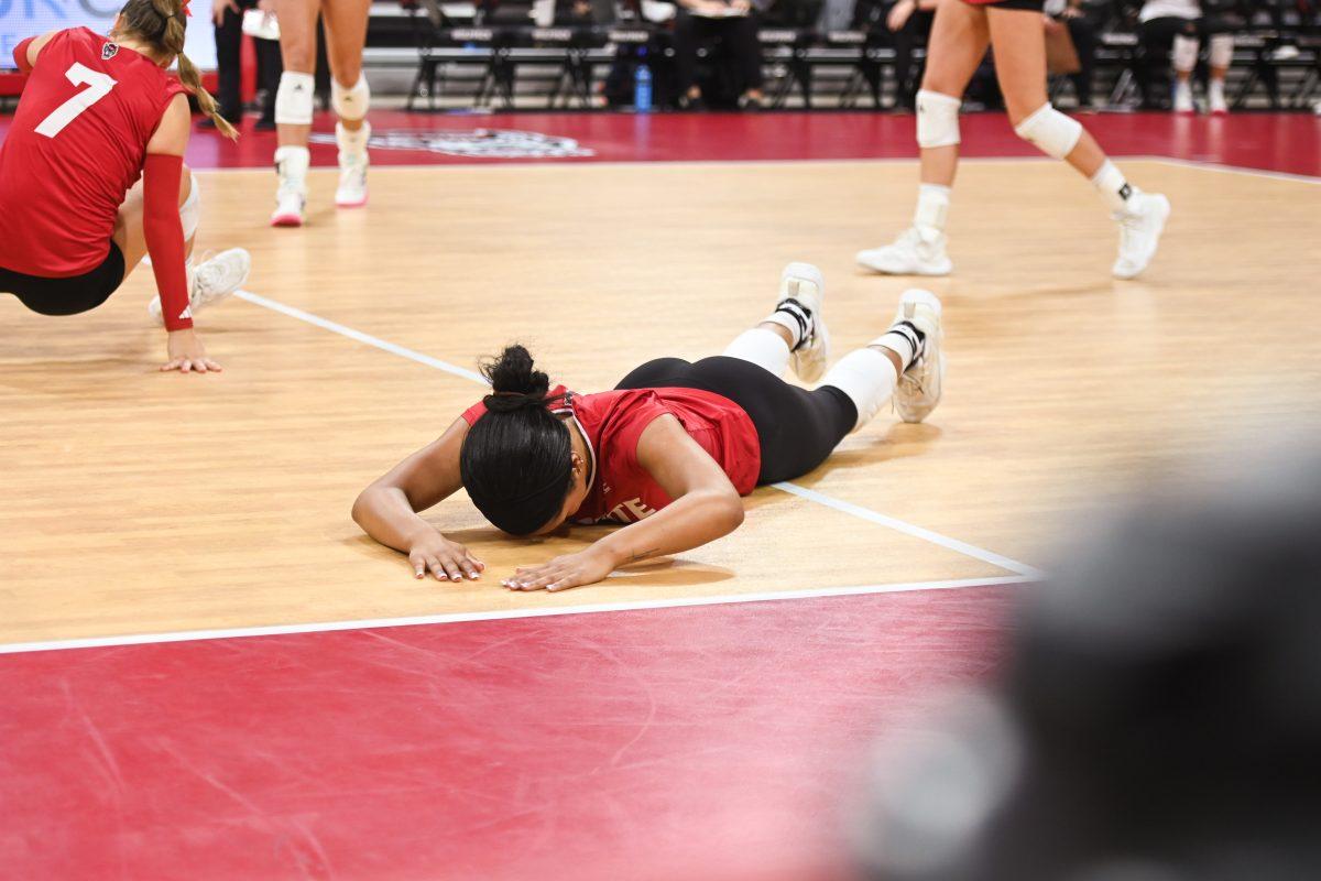 Senior middle blocker Jada Allen lays on the floor after failing to save the ball in the NC State Wolfpack's home game against the UVA Cavaliers on Sunday, Sept. 29, 2024. The Wolfpack went on to defeat the Cavaliers 3-1.