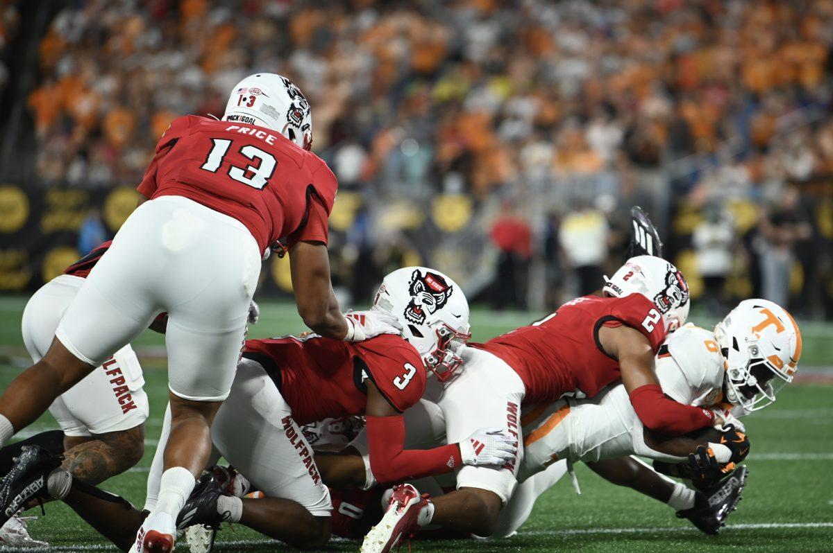 Redshirt junior defensive lineman Travali Price, graduate cornerback Aydan White and sophomore cornerback Brandon Cisse tackle a Volunteer runningback during the Wolfpack's game against the Tennessee Volunteers in Bank of America Stadium for the Duke's Mayo Classic on Saturday, Sept. 8, 2024. The Wolfpack lost to the Volunteers 51-10.