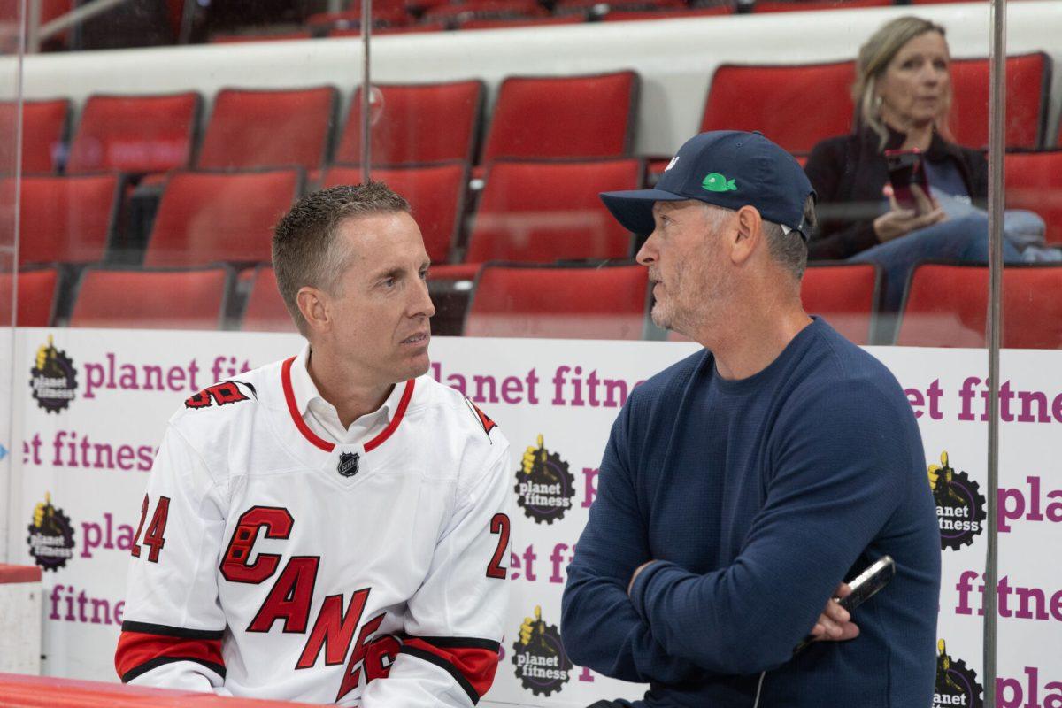 Carolina Hurricanes owner Tom Dundon and Lenovo&#8217;s, SVP and President of North America, Ryan McCurdy chat while sitting on the Canes bench at the Lenovo Center unveiling on Thursday, Sept. 19, 2024. The event celebrates the beginning of Lenovo's naming rights agreement.
