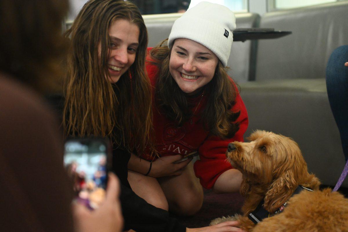 Peyton Greenway, a first-year in exploratory studies, and Carina Elrod, a first-year studying environmental sciences, take a photo with Belle at Pause for Paws at D.H. Hill Jr. Library on Tuesday, Sept. 17, 2024. Pause for Paws was an event that allowed students to relax and de-stress with service dogs from Canines for Service.
