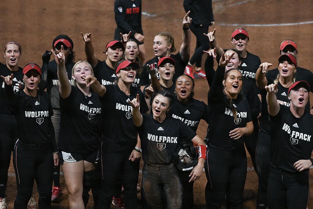 The team throws up wolfies while leading a chant during the game against Elon at Dail Softball Stadium on Wednesday, Oct. 23, 2024. The Wolfpack won the game 14-7.