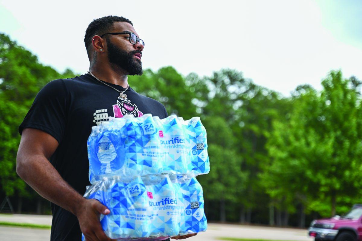 Davin Vann, a graduate student and defensive captain of the NC State football team, carries water bottles during NC State's Football Hurricane Relief Drive at Close-King Indoor Practice Facility on Tuesday, Oct. 1, 2024. The drive was led by defensive captain Vann. Community members were able to donate water, hygiene products, canned food and blankets from Sept. 30 to Oct. 2.