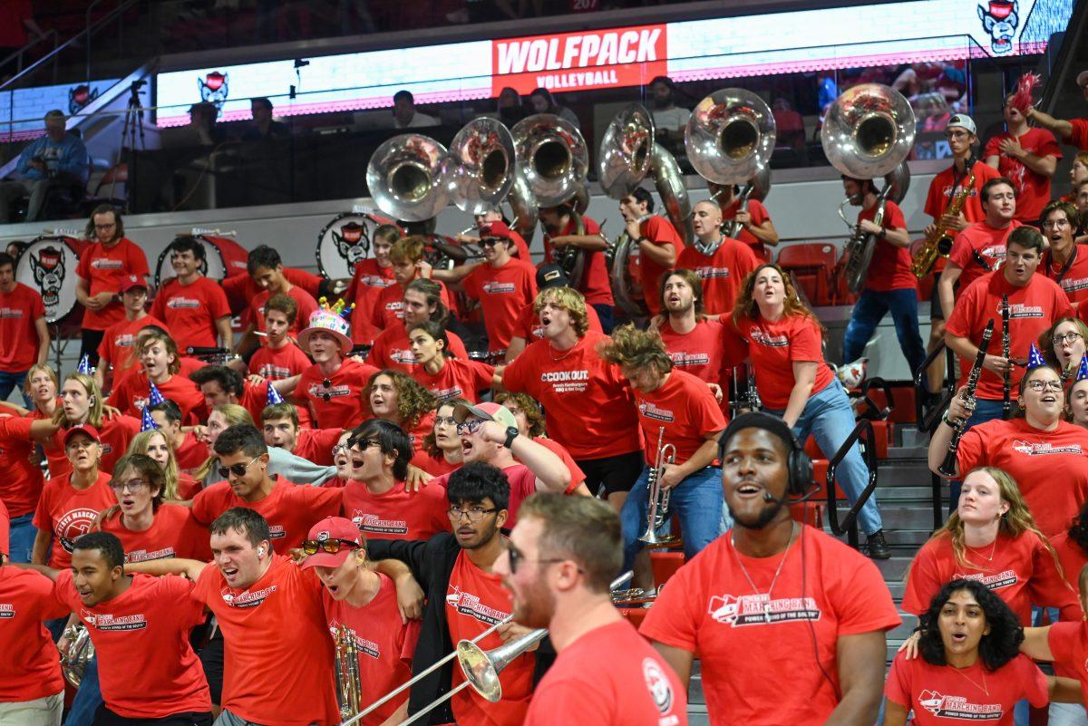 The Wolfpack Band excitedly dance on the bleachers after the volleyball team earns a point during the match against UNC-Chapel Hill on Friday, Oct. 11, 2024. The Wolfpack defeated the Tar Heels 3-1. The Wolfpack Band was present at the game in support of the volleyball team along with a record-breaking crowd.
