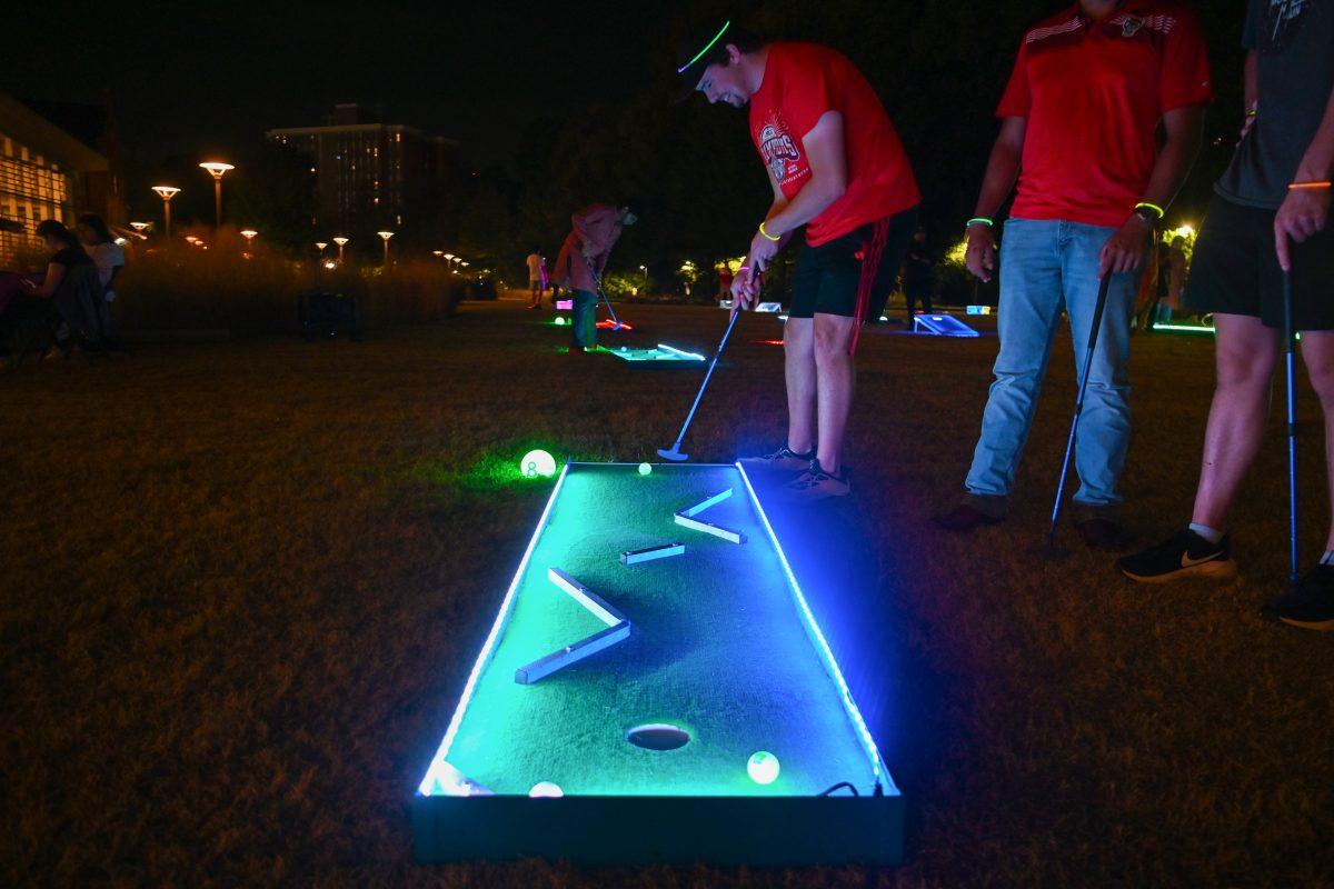 JT Raymond, a fourth-year studying technology, engineering and design education, plays mini golf during the Glow Up for Mental Health event at Stafford Commons on Wednesday, Nov. 6, 2024. The Glow Up for Mental Health event included a DJ-led neon dance party, neon mini golf and lawn games and campus partners tabling to build community and reduce mental health stigma.