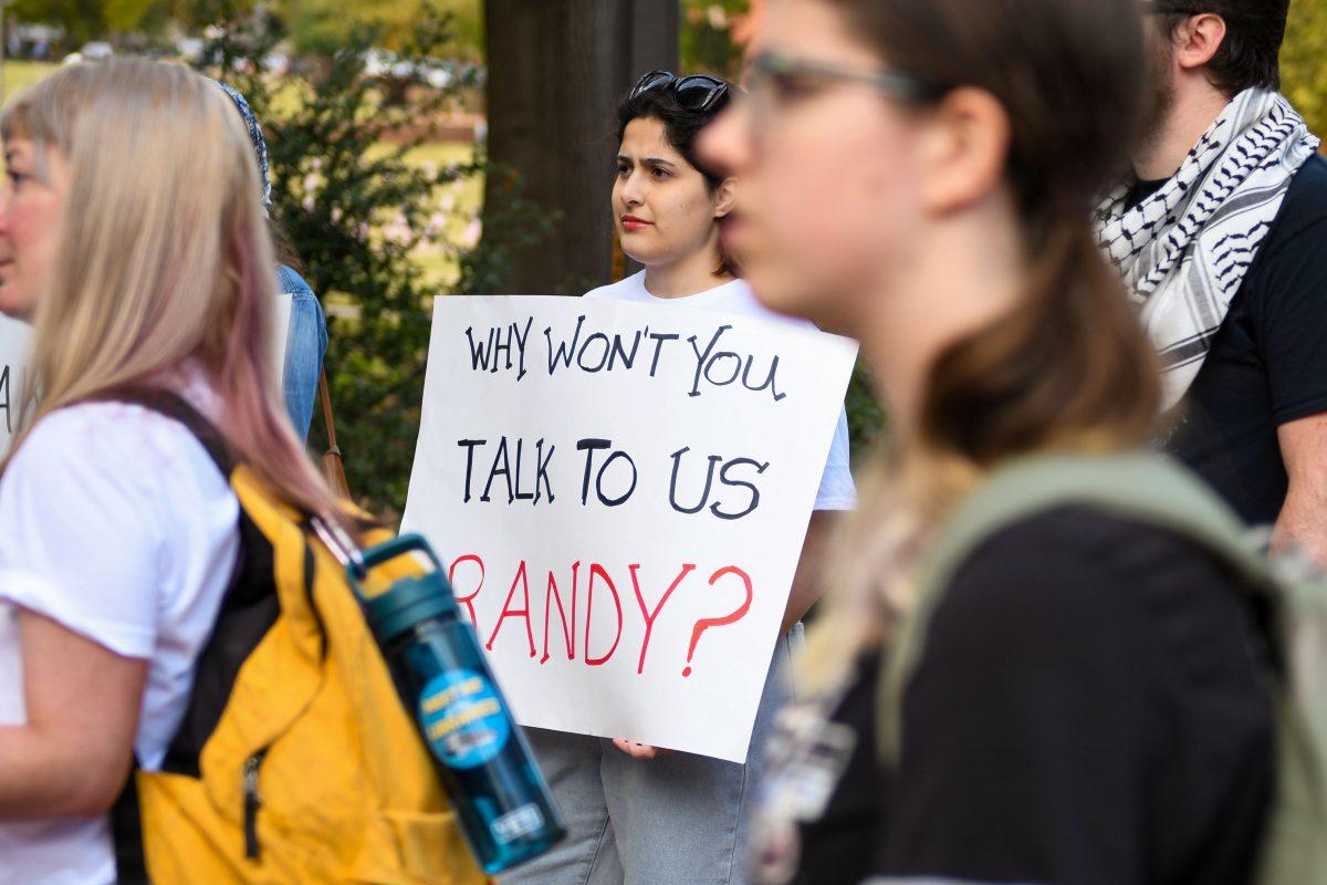 Nay Achkar, a graduate student studying public history, holds a sign, inscribed with "Why won't you talk to us Randy?" outside of Poe Hall on Tuesday, Nov. 19th, 2024. "I want justice to the people suffering", stated Nay.