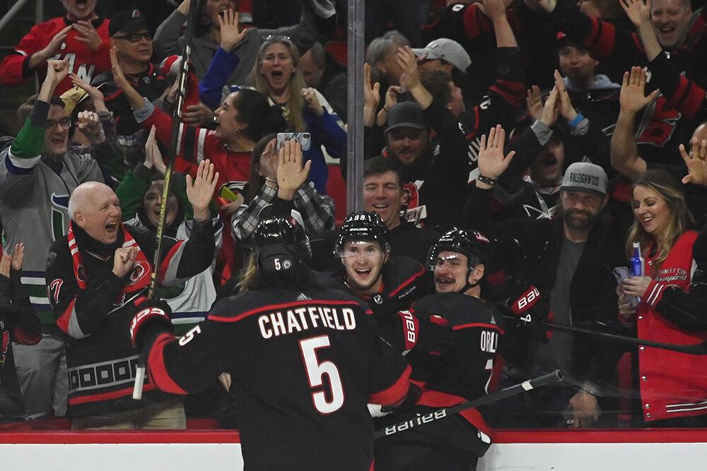 Carolina players Jalen Chatfield, Martin Necas and Dmitry Orlov celebrate against the glass after Orlov's game winning goal during the Hurricanes' home game against the Arizona Coyotes in PNC Arena on Saturday, Jan. 27, 2024. Orlov scored the winning goal with under a minute to go in the third period. The Hurricanes beat the Coyotes 3-1.