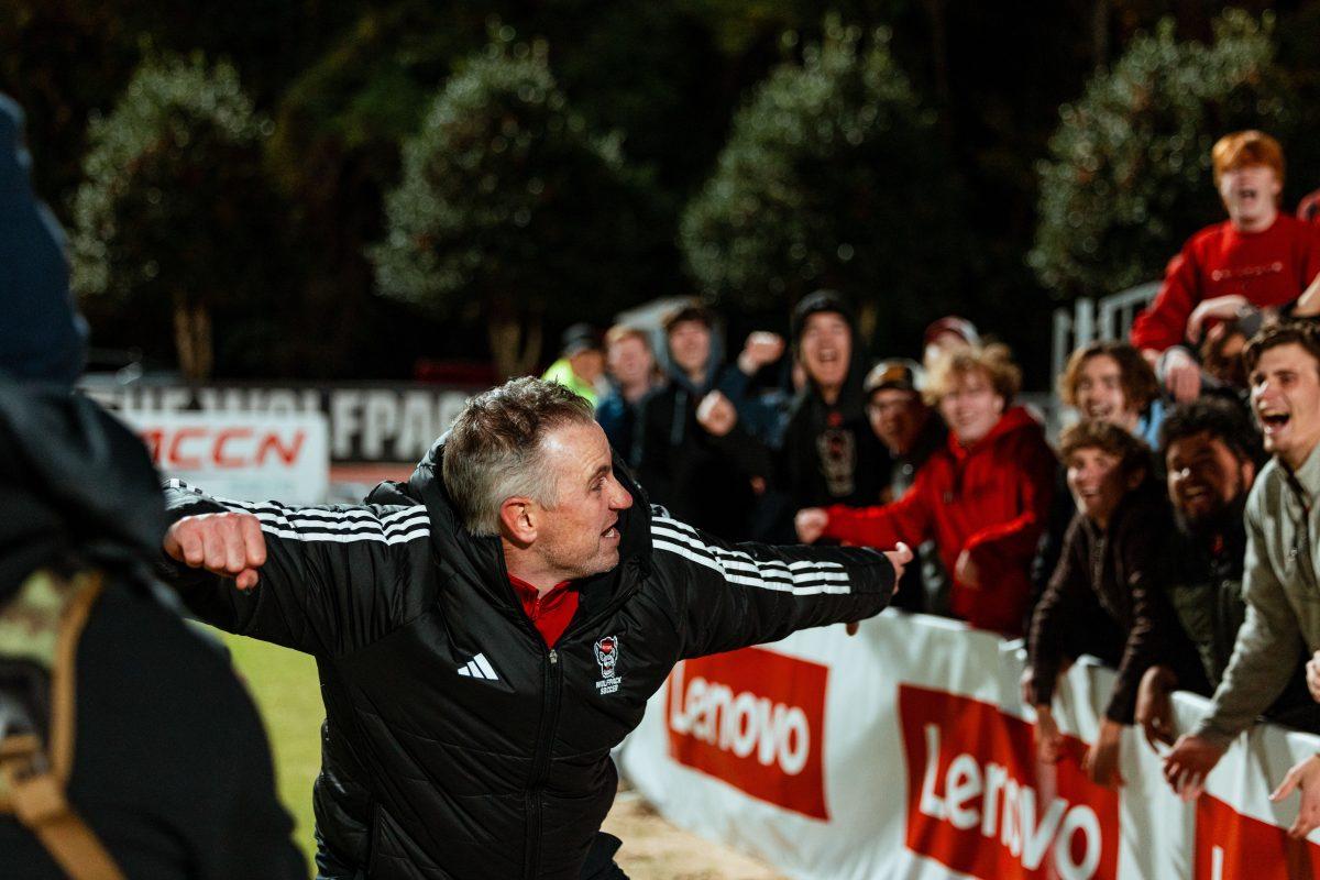 Head coach Marc Hubbard celebrate with the student section "The red terrors" after their win during the Wolfpack's first round home playoff game against the Charlottle 49ers at Dail Soccer Field on Thursday, Nov. 21, 2024. The Wolfpack beat the 49ers 2-1 in double overtime.