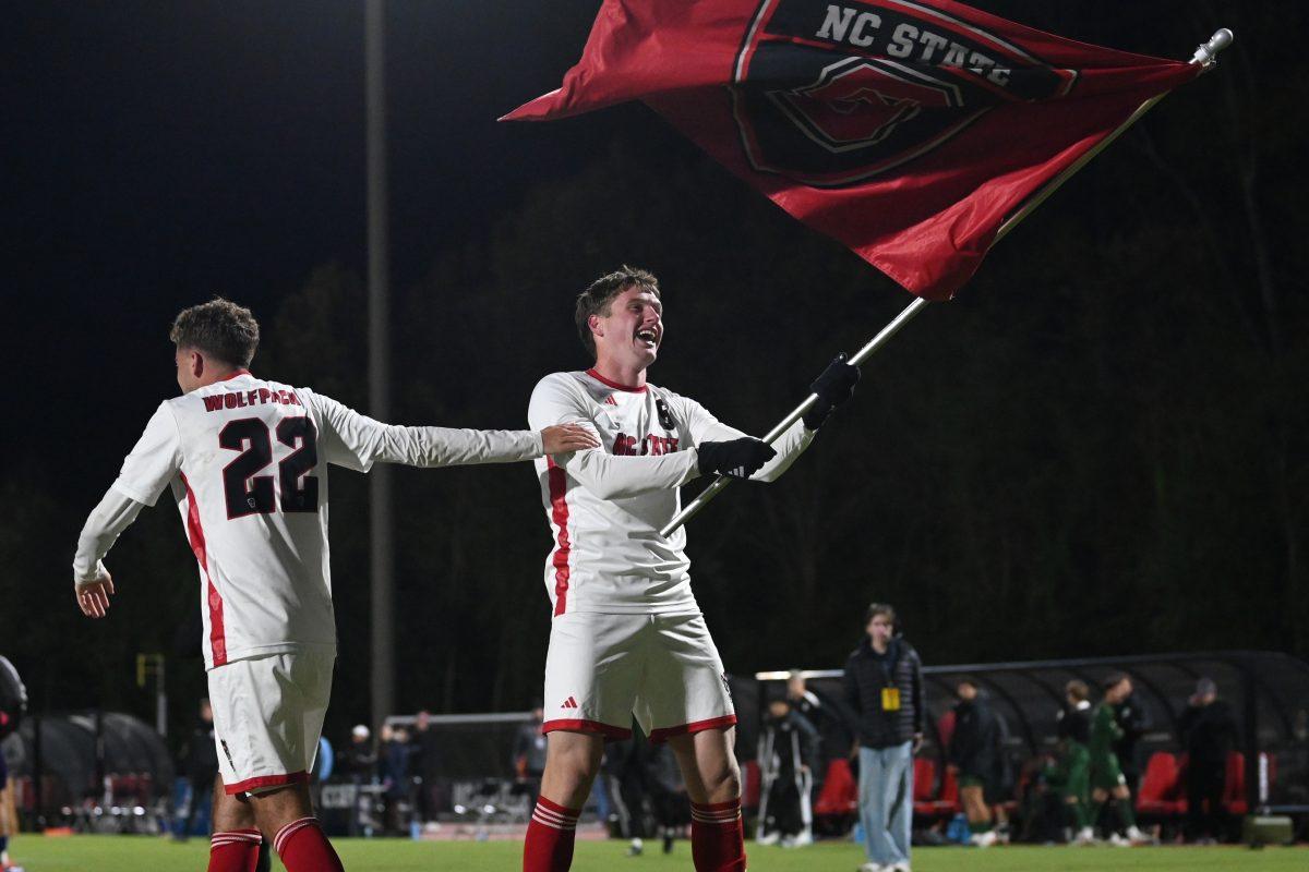 Freshman defender Niko Markovic waves around a flag given to the team by a fan after NC State's NCAA first round game against Charlotte at Dail Soccer Field on Thursday, Nov. 21, 2024. Markovic scored in double overtime to send the Wolfpack to the next round. The Wolfpack beat the 49ers 2-1.