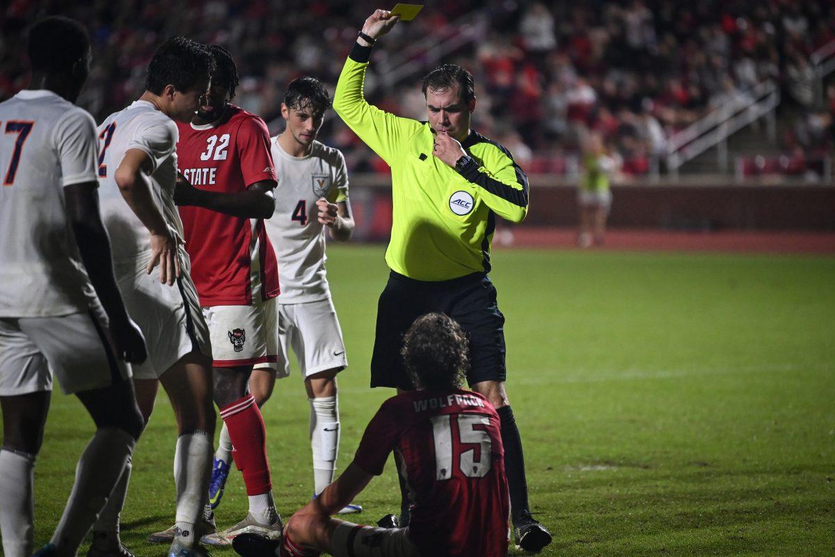 Redshirt junior forward Aidan Payne sits back on the ground as he is given a yellow card during NC State's ACC playoff game against Virginia at Dail Soccer Field on Wednesday, Nov. 6, 2024. Virginia mounted a second half comeback to beat NC State 2-1.