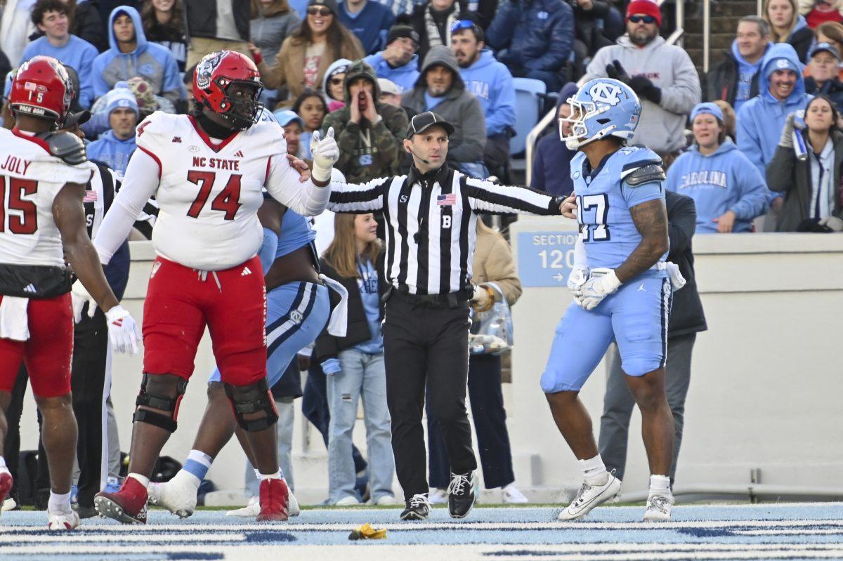 Back judge Frederick Dimpfel holds back graduate offensive tackle Anthony Belton and a UNC-Chapel Hill player during the football game against UNC-Chapel Hill at Kenan Stadium on Saturday, Nov. 30, 2024. NC State beat UNC 35-30.