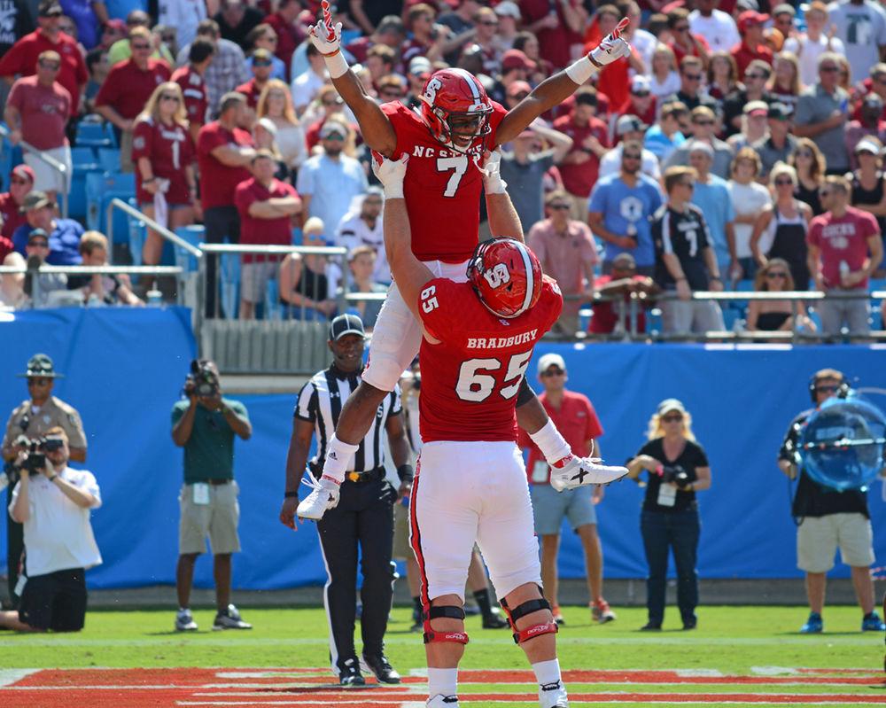 Junior running back Nyheim Hines is lifted by redshirt junior offensive guard Garrett Bradbury after scoring a touchdown. The Wolfpack lost the game by a score of 35-28 in Bank of America Stadium in Charlotte on Sept. 2, 2017.
