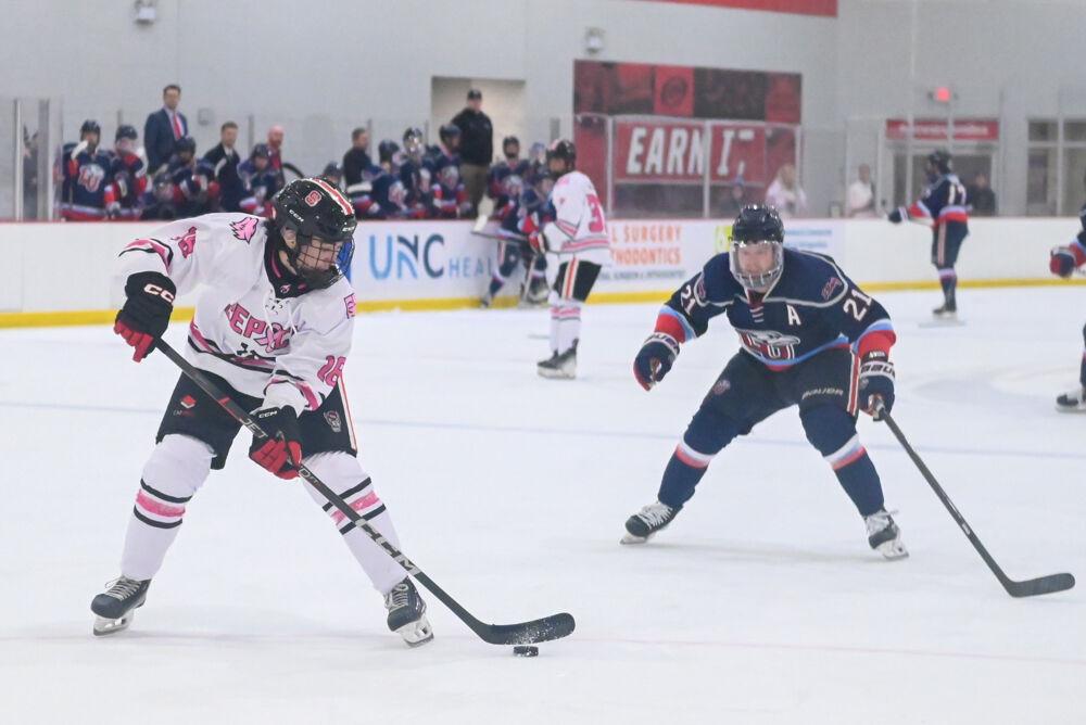 Sophomore defenseman Andrew Throndson protects the puck from an approaching opponent during the game against Liberty University at Invisalign Arena on Friday, Jan. 17, 2025. The Wolfpack lost to the Flames 5-4.