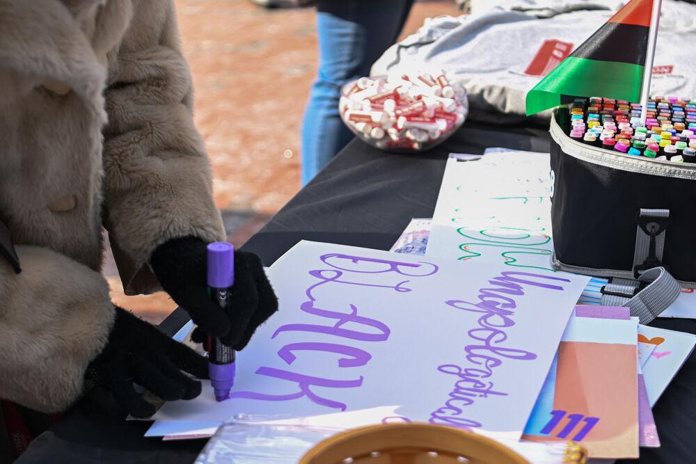 A participant writes on a poster during March Like Martin from Stafford Commons to Harris Field on Friday, Jan. 24, 2025. Posters that were made featured quotes and slogans that promoted Martin Luther King' s message.