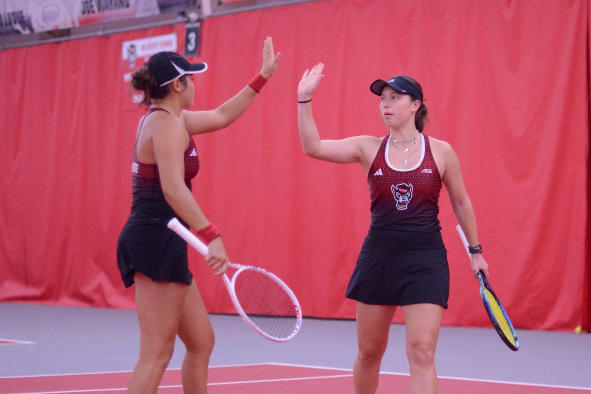 Freshman Mia Slama and junior Anna Zyryanova high five after scoring a point during their doubles match against Pepperdine at J.W. Isenhour Tennis Center on Saturday, Jan. 19, 2025. NC State defeated Pepperdine 5-2.