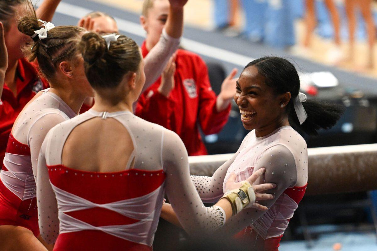 Sophomore Elle Hadrick and freshman Caroline Volk congratulate freshman Syniya Thomas on her routine on the balance beam during the meet against UNC-Chapel Hill in Carmichael Arena on Friday, Jan. 24, 2025. Thomas earned a 9.800 on the balance beam. The Wolfpack beat the Tar Heels 196.350-195.925.