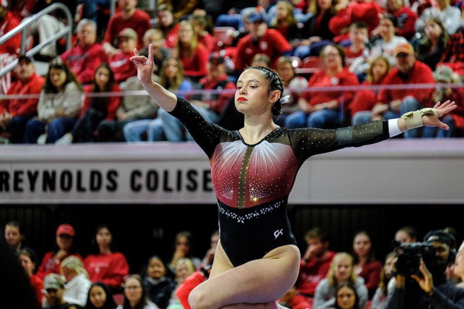 Graduate Chloe Negrete puts up a "wolfie" on the balance beams during the meet against UNC-Chapel Hill&#160;at Reynolds Coliseum on Friday, Feb. 21, 2025. Negrete scored a 9.975 on the floor exercise. NC State beat UNC 197.025-195.500.