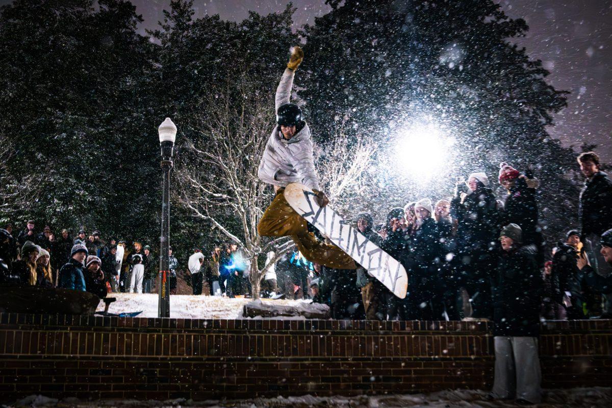 Ben Palmer, a senior studying industrial design, hits a trick over a snow ramp in the Court of North Carolina on Tuesday, Jan. 21, 2025. Palmer and other members of the Ski and Snowboard Club made use of the snow on campus to build a ramp to jump off of. Students gathered in the Court of North Carolina to celebrate and enjoy the snow.