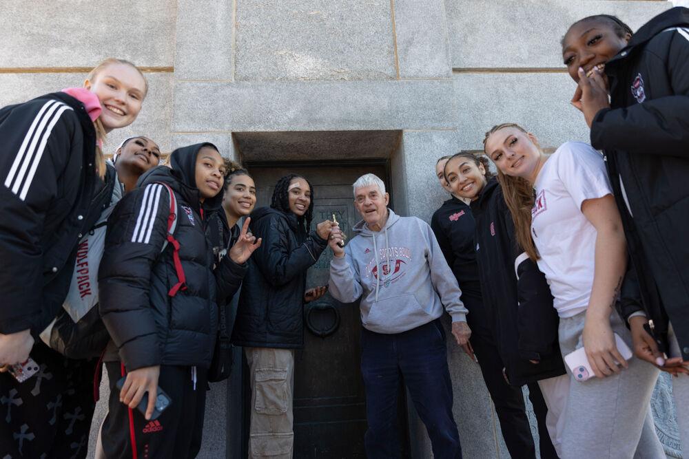 Dr. Thomas Stafford and the Wolfpack women's basketball team celebrate the team's victory at the Memorial Belltower on Sunday, Feb. 23, 2025. NC State defeated top-ranked Notre Dame 104-95.