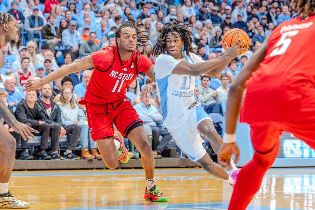 Sophomore guard Dennis Parker attempts to guard his opponent during the game against the University of North Carolina in the Dean E. Smith Center on Wednesday, Feb. 19, 2025. Parker, Jr. scored three points and made one rebound. NC State lost the game 97-73.