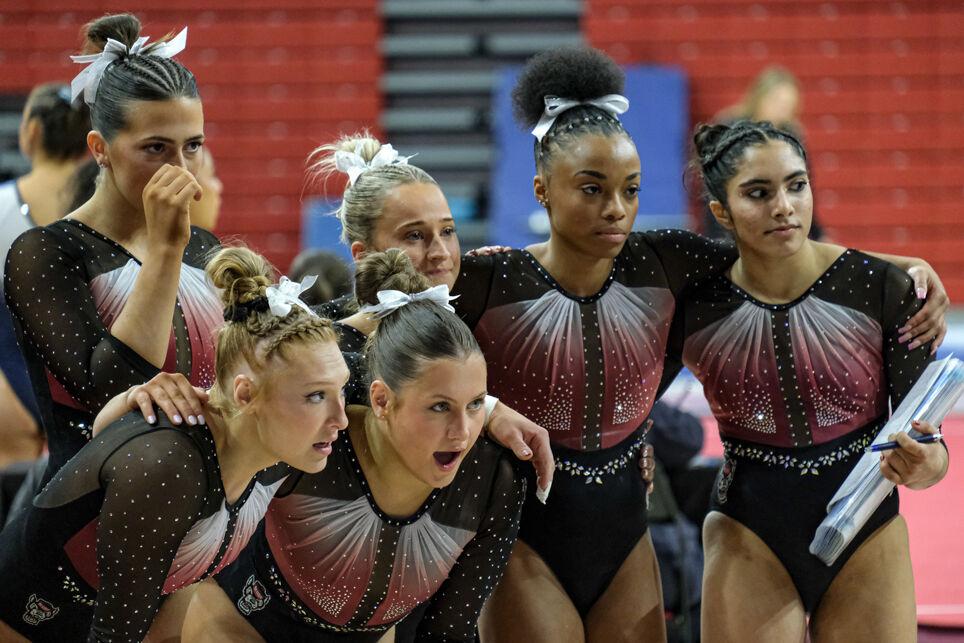 Members of the NC State gymnastics team watch a balance beam performance during the meet against UNC-Chapel Hill&#160;at Reynolds Coliseum on Friday, Feb. 21, 2025. NC State scored a combined 49.250 on the uneven bars. NC State beat UNC 197.025-195.500.