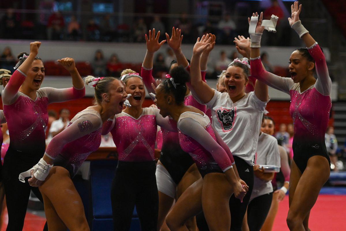 The NC State Women's Gymnastics team celebrates after a completed event on vault during the meet against the University of Pittsburgh in Reynolds Coliseum on Saturday, Feb. 8, 2025. The combined team score for the vault event was 48.925. The Wolfpack beat the Pitt Panthers 196.475 to 193.600.
