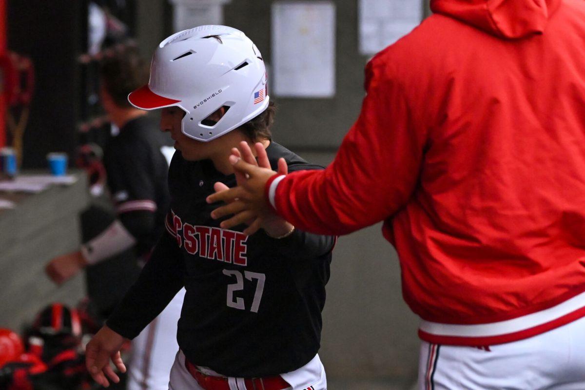 Sophomore infielder Chris McHugh celebrates with a teammate after scoring a run during the game against Fordham on Feb. 15, 2025 at Doak Field at Dail Park. McHugh scored a total of three runs. The Wolfpack defeated the Rams 19-6.