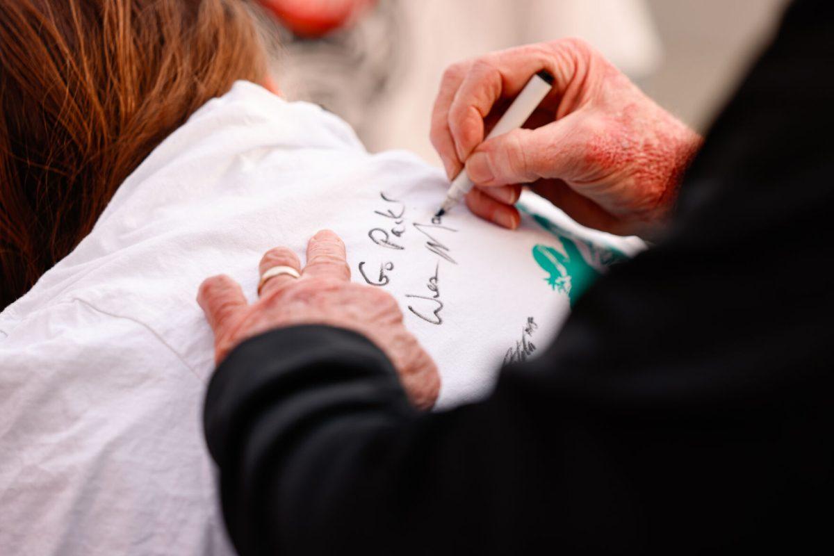 Women's basketball head coach Wes Moore signs a fans t-shirt during the teams welcome back to Reynolds Coliseum on Saturday, March 29.