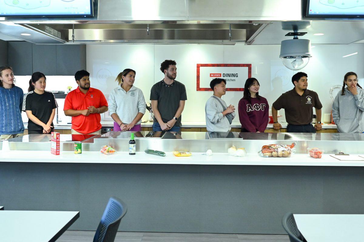 Both teams of students line up to hear what the secret ingredients of their challenge are during the MGC Chopped: Cooking Competiton at Carmichael Gym on Wednesday, March 26, 2025. The event was organized by members of the Multicultural Greek Council.