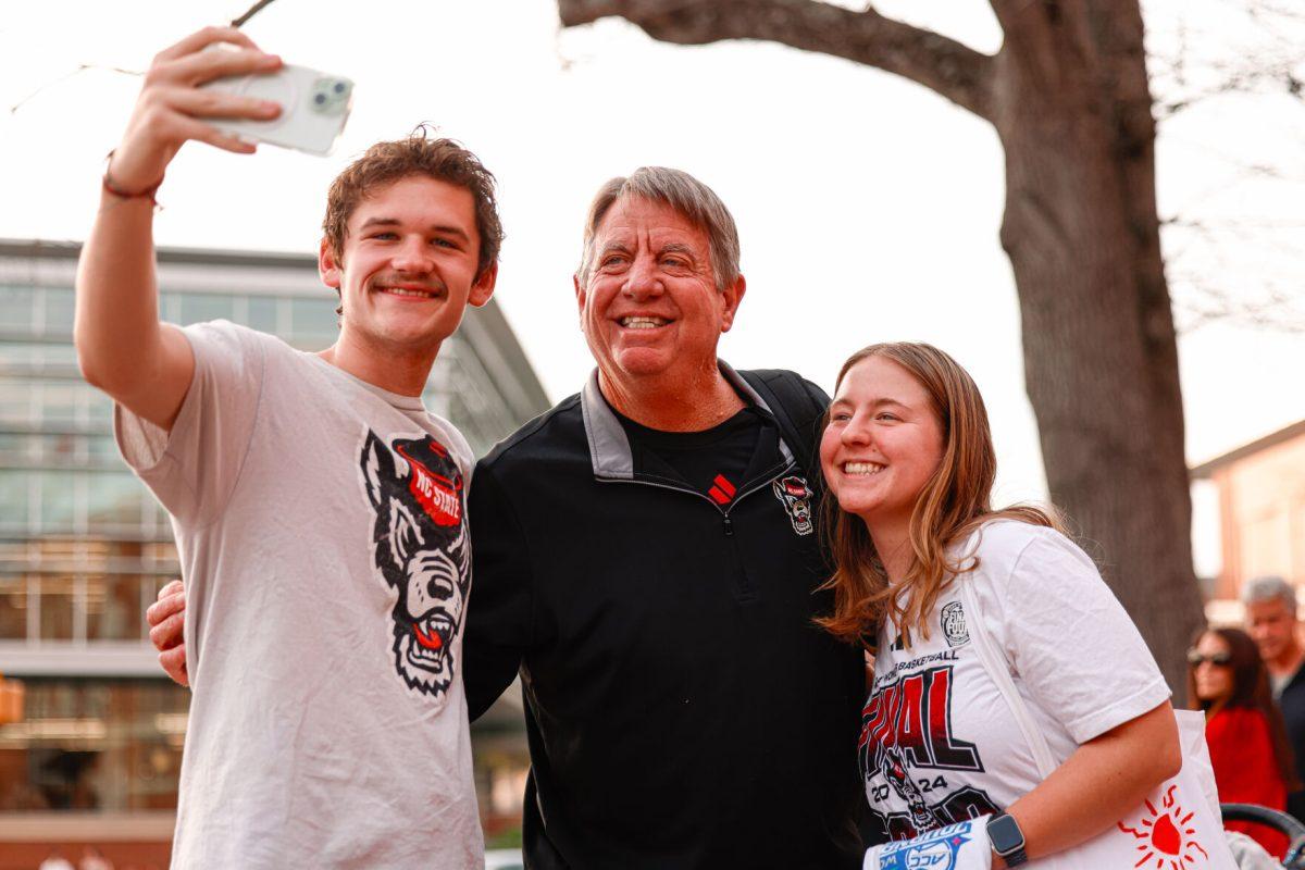 Women's basketball head coach Wes Moore takes a selfie with a couple of fans during the teams welcome back to Reynolds Coliseum on Saturday, March 29.