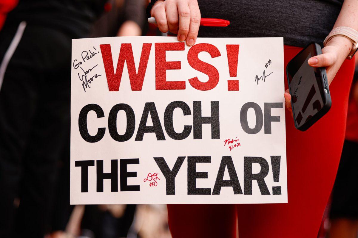 A fan holds up a "Coach of the Year" sign for the head coach Wes Moore during the team's welcome back to Reynolds Coliseum on Saturday, March 29. Moore is a Naismith Coach of the Year semifinalist.
