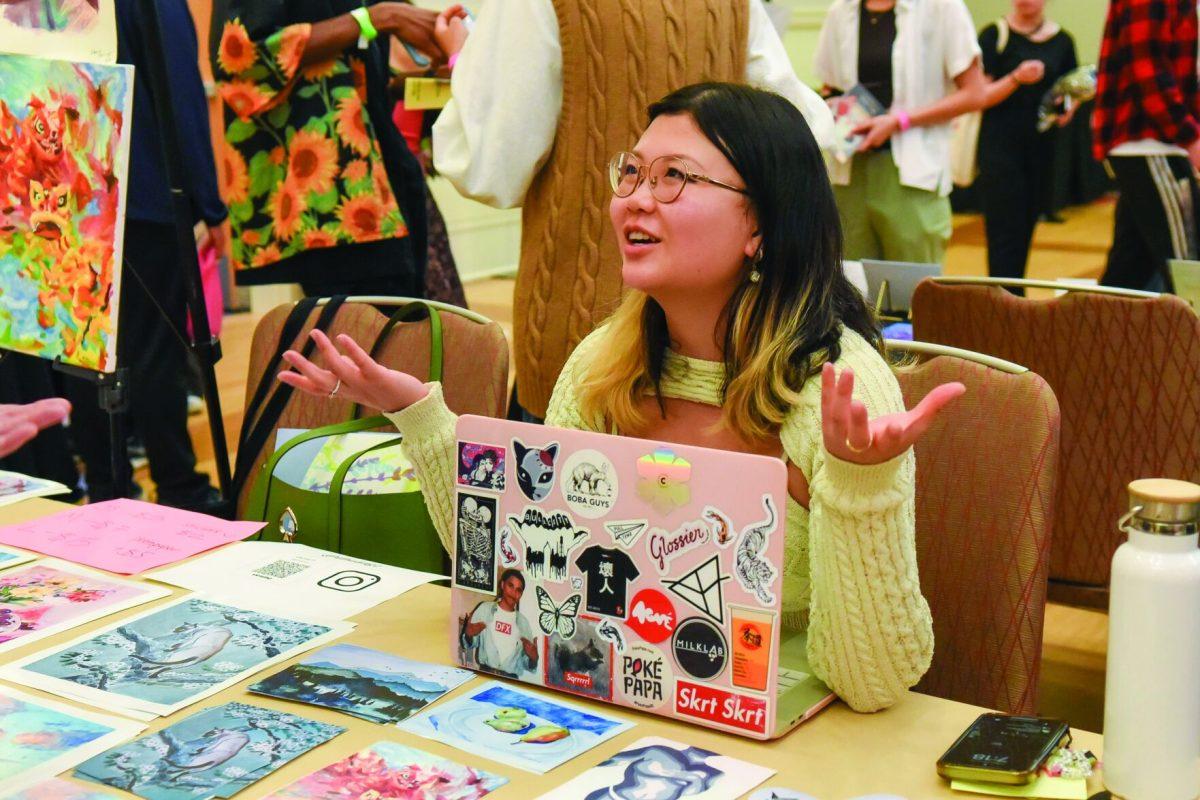 Denna Huang talks to visitors at her table during the Asian Artist Showcase in the Talley Ballroom on Friday, March 31, 2023. Artists at the event sold their art, such as painting and photography, to visitors and students.