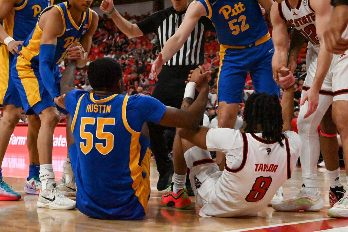 Senior guard Jayden Taylor and Pitt senior forward Zack Austin help one another up during the game against Pitt in the Lenovo Center on Wednesday, March 5, 2025. The Wolfpack beat the Panthers 71-63.