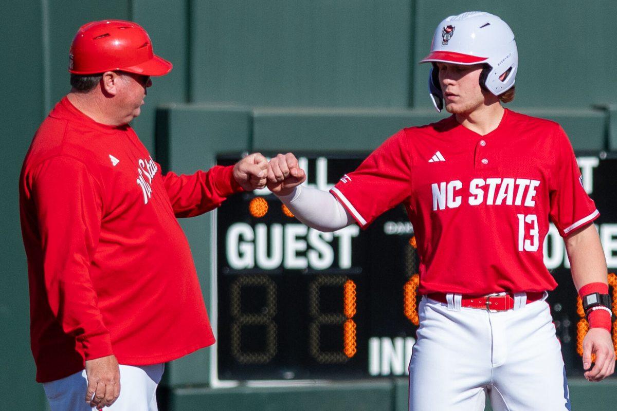 Sophomore catcher Alex Sosa fist bumbs the third base coach after getting to third during the game against Canisius at Doak Field at Dail Park on Feb. 28, 2025. Sosa accounted for two hits and two runs. NC State beat Canisius 10-2 in the first game of the series.
