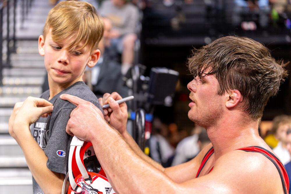 Redshirt junior Isaac Trumble signs a child's shirt during the NCAA Wrestling Championship Tournament in the Wells Fargo Center on Thursday, March 20, 2025. Trumble finished fourth for the heavyweight class. NC State finished eighth overall with 46.5 points.