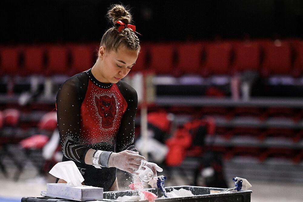 Freshman Jenna Rusk chalks up before her routine on the uneven bars during the meet against Ohio State in Reynolds Coliseum on Friday, March 7, 2025. NC State beat Ohio State 197.000-196.325.
