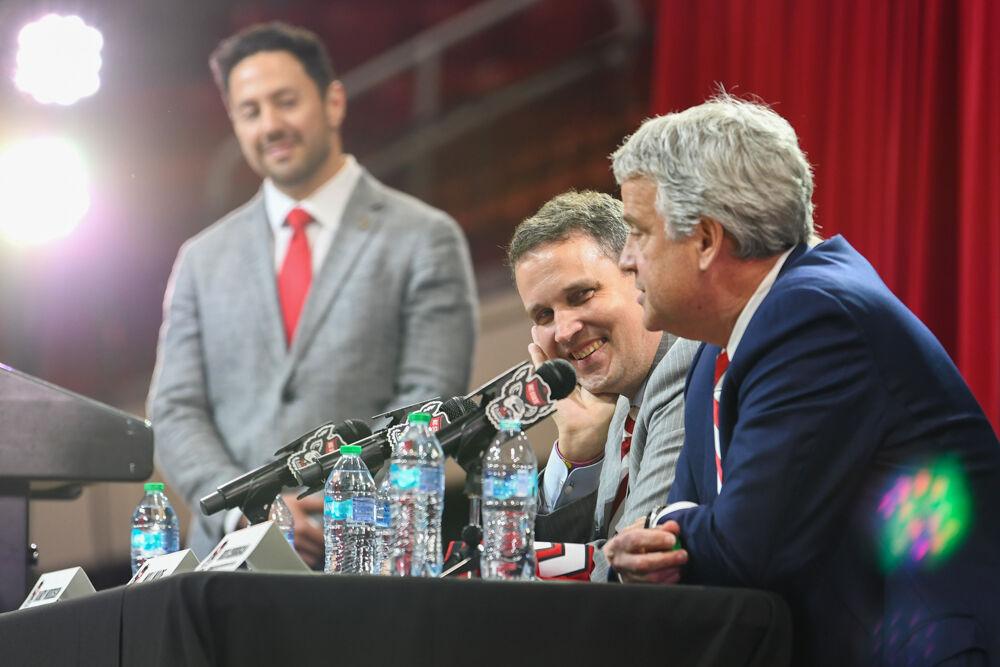 Will Wade, the new head coach of NC State men's basketball, smiles at Boo Corrigan, McMurray Family Director of Athletics, during a press conference discussing Wade's hiring inside Reynolds Coliseum on Tuesday, March 25, 2025. Wade will serve as the new men's basketball coach after having been at McNeese State.