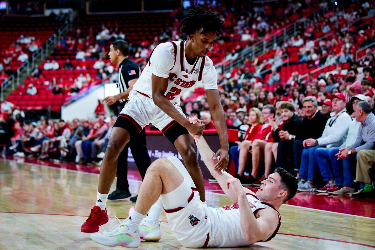 Freshman guard Paul McNeil helps up graduate guard Michael O'Connell during the game against Pitt in The Lenovo Center on Wednesday, March 5, 2025. The Wolfpack beat the Panthers 71-63.