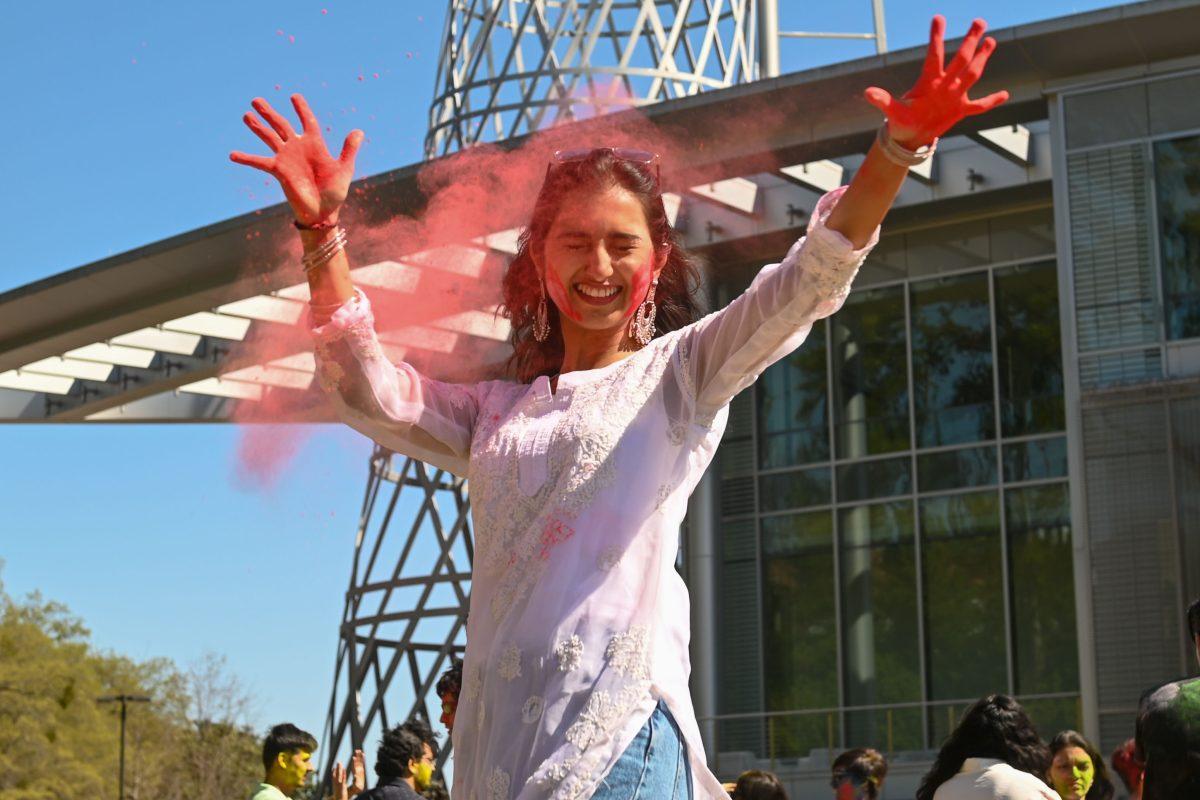 Akshatha Cheppudira, a graduate student studying industrial engineering, throws color while smiling during Holi at Stafford Commons on Saturday, March 22, 2025. Holi was thrown by EKTAA, NC State's South Asian Student Association.