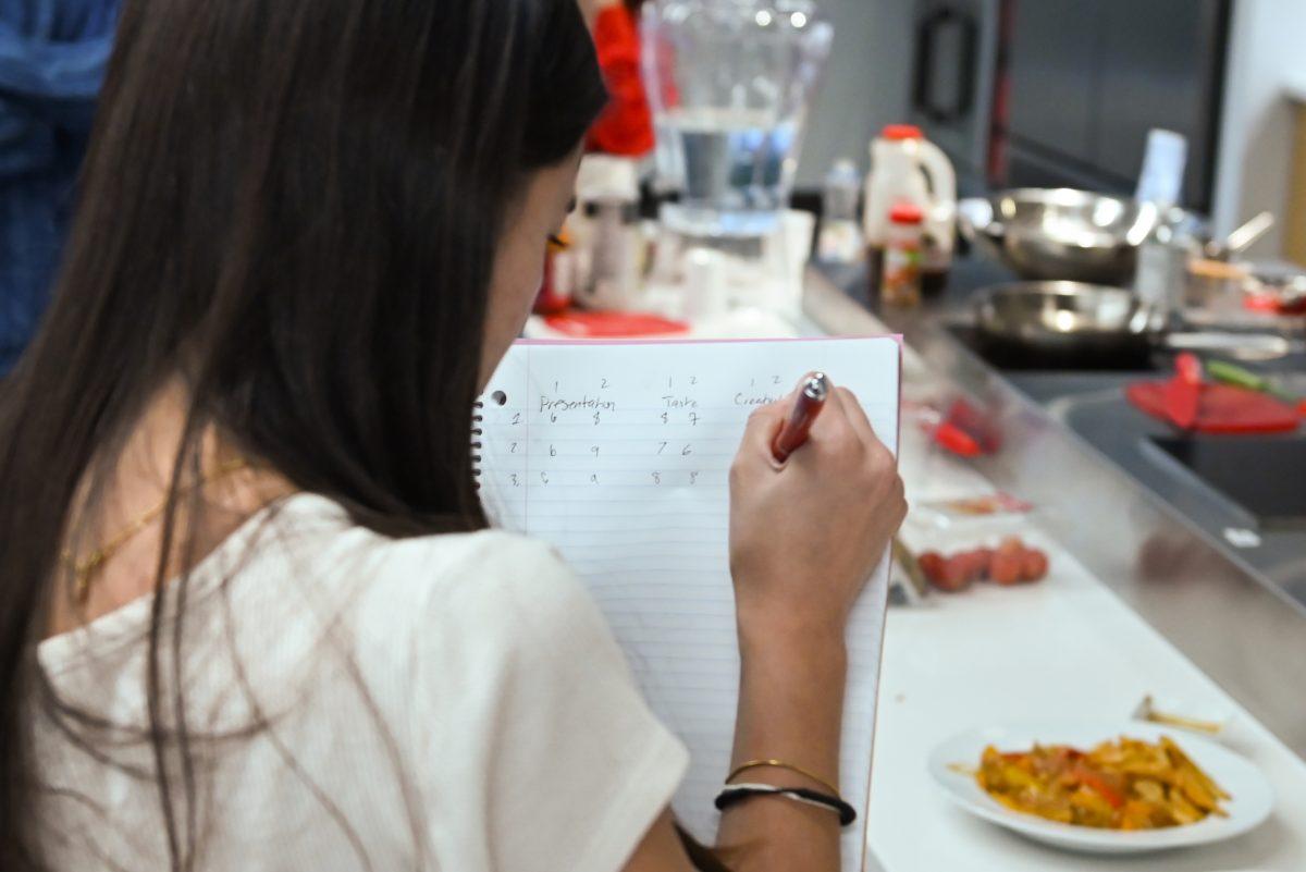 Kalea Davis, a third-year studying biomedical engineering, writes down her score for creativity while judging the final dishes during the MGC Chopped: Cooking Competiton at Carmichael Gym on Wednesday, March 26, 2025. The event was a part of MGC Week and students were encouraged to channel their inner "Top Chef."