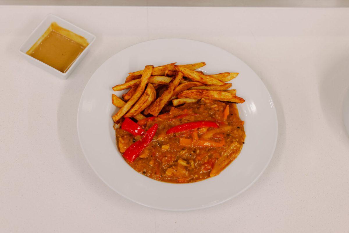 The final dish of team one during the MGC Chopped: Cooking Competition at Carmichael gym on Wednesday, March 26, 2025. The dish included curry, french fries, peppers, onions, chicken, tomatoes, coconut milk, and honey mustard sauce garnished with pomegranate seeds.