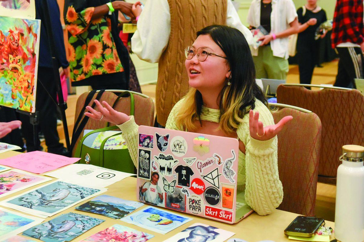 Denna Huang talks to visitors at her table during the Asian Artist Showcase in the Talley Ballroom on Friday, March 31, 2023. Artists at the event sold their art, such as painting and photography, to visitors and students.